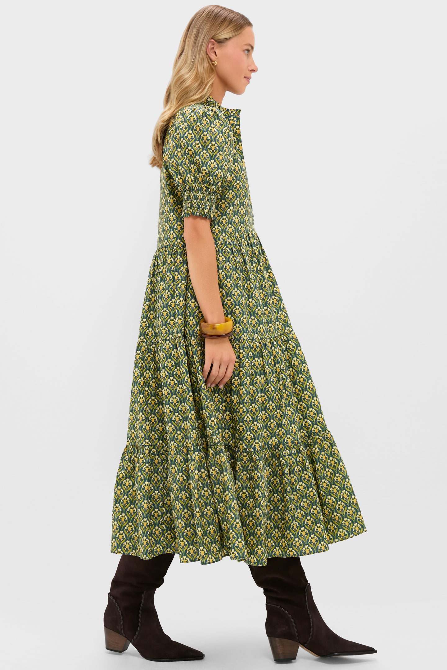 Model in profile wearing the Forest Green Floral Bennett Maxi Dress, featuring a classic tiered silhouette, puff sleeves, and paired with boots for an effortless, fun, high-end look.