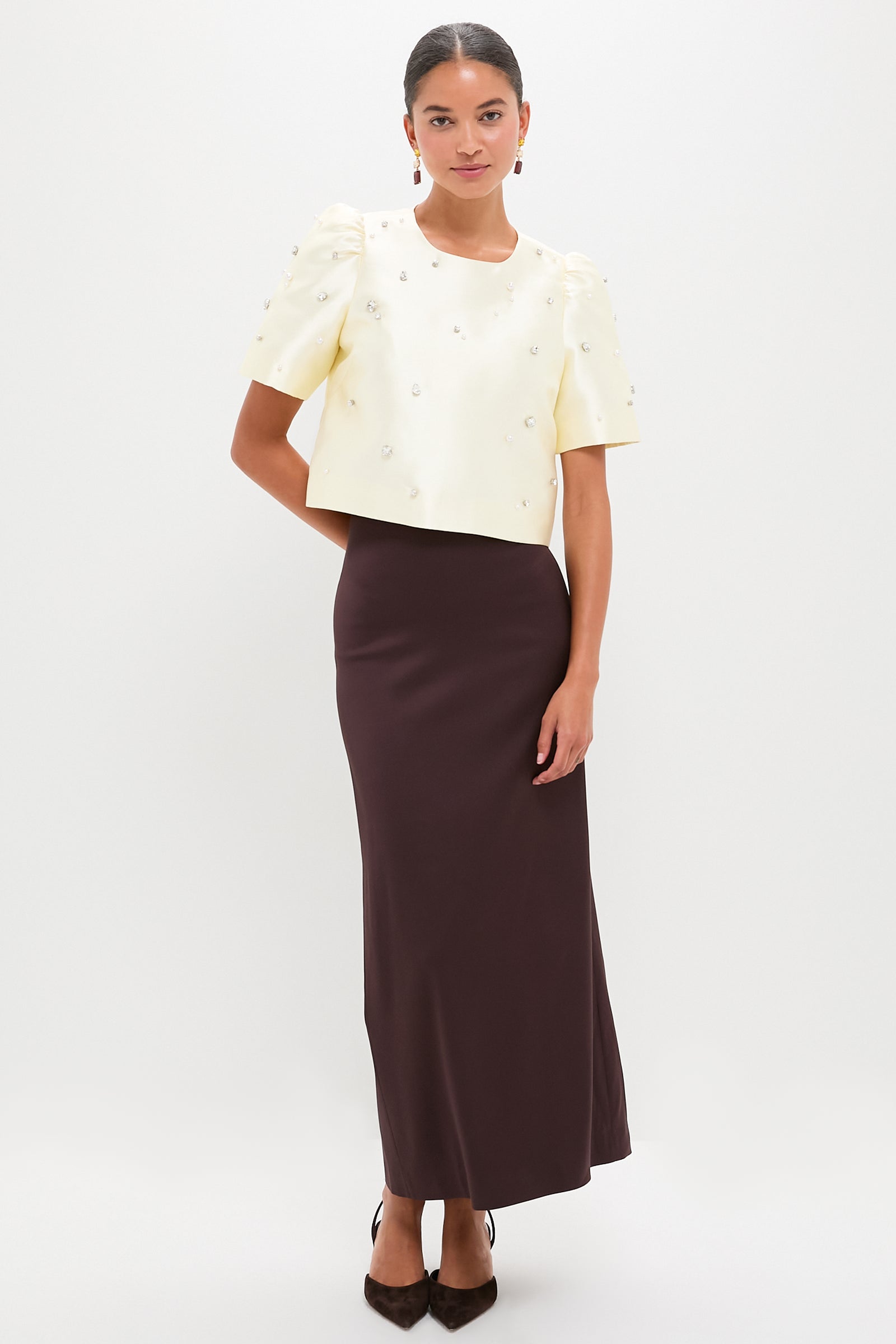 Model wearing the classic Ivory Olivia Top with pearl and rhinestone details, paired with a high-end brown column skirt, embodying an effortless, fun, and modern look.