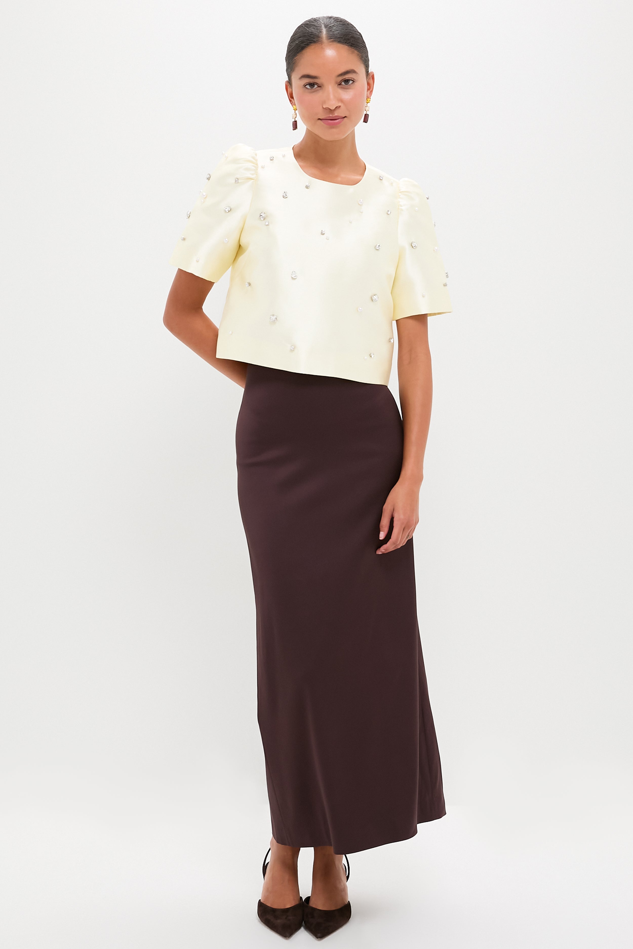 Model wearing the classic Ivory Olivia Top with pearl and rhinestone details, paired with a high-end brown column skirt, embodying an effortless, fun, and modern look.