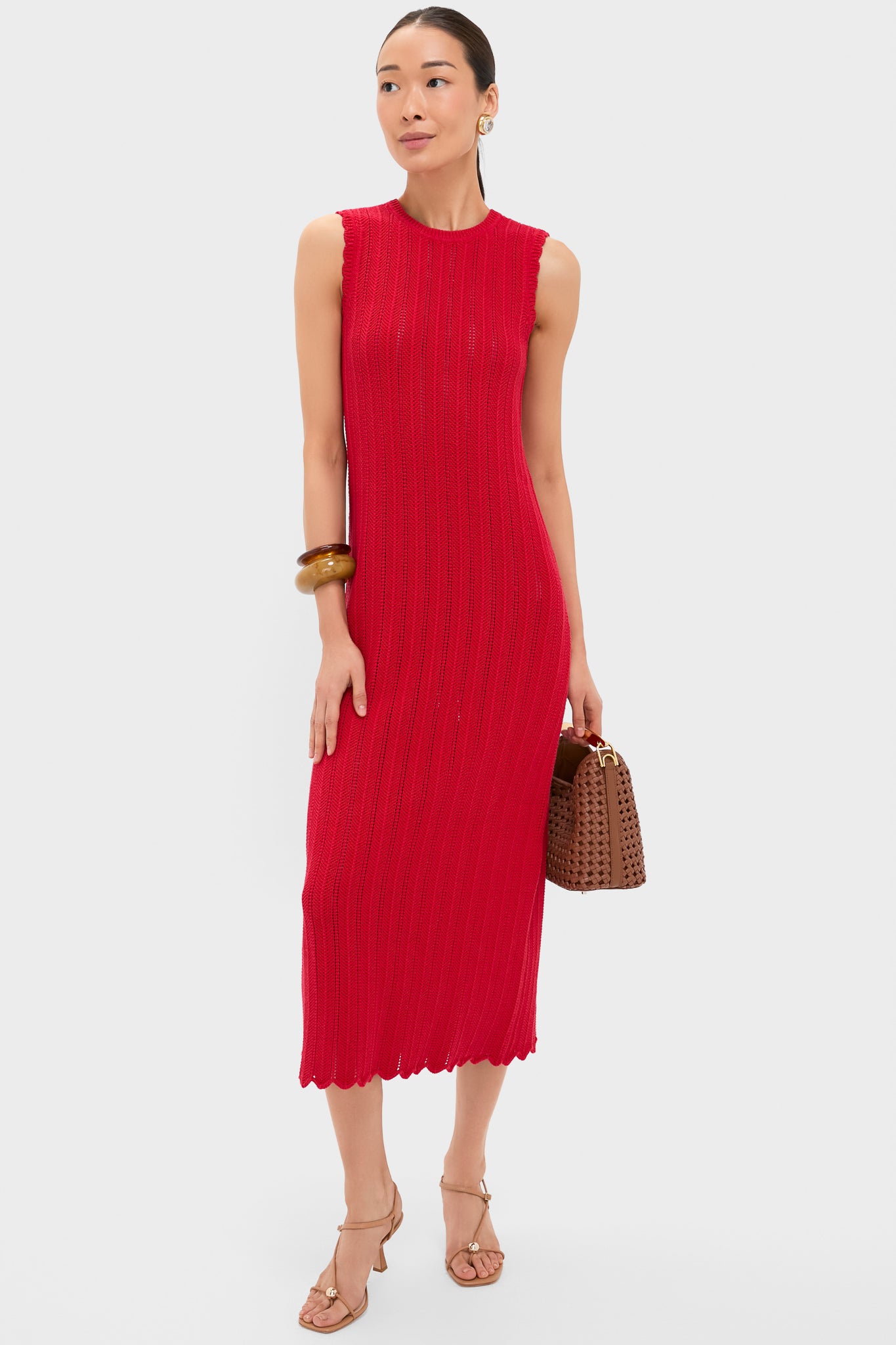 Woman wears Altuzarra luxury Grenadine Sissi Dress, tan heeled sandals, carries a brown textured handbag, and accessorizes with gold hoop earrings and a chunky bangle.