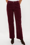 Person wearing high-waisted burgundy corduroy pants by Alex Mill paired with black pointed-toe shoes.