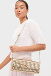 A woman in a textured white top holds the Billini Alice clutch, a gold quilted evening bag with shoulder strap and top handle, against a plain background.