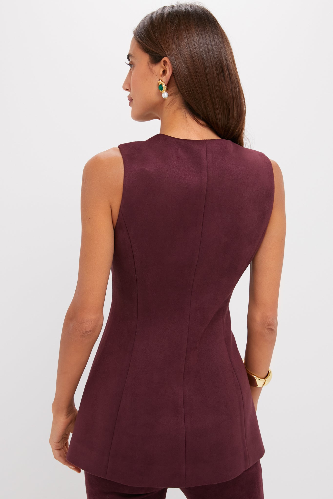 Woman in sleeveless Winetasting Vegan Suede Rhoda Tunic Top with chic silhouette, paired with matching pants, gold bracelet, and statement earring, embodying effortless high-end style.
