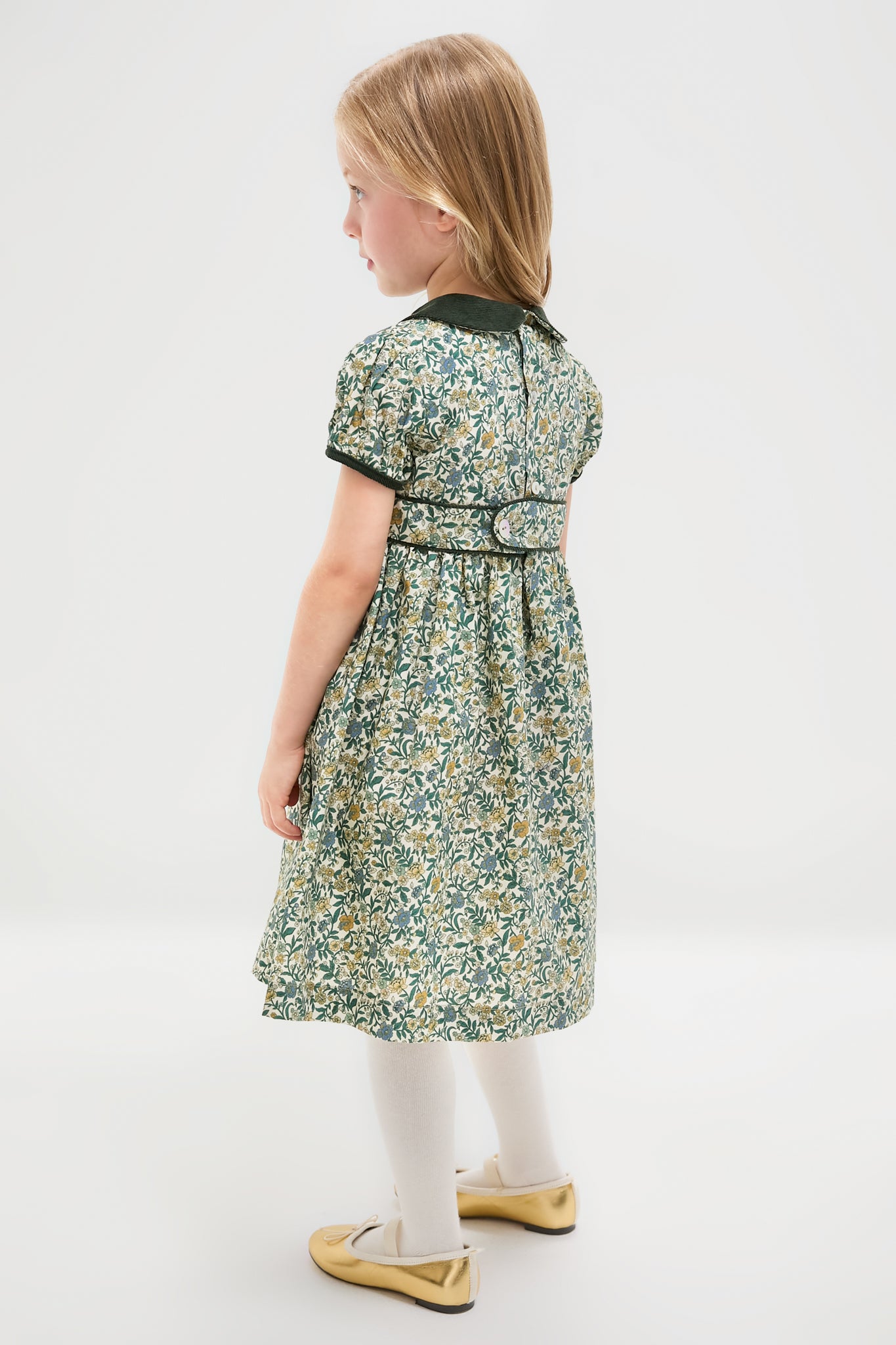 Child in classic Bottle Green Floral Portia Girl Dress with Peter Pan collar, cap sleeves, and fit-and-flare silhouette, embodying effortless, high-end style paired with gold ballet flats.