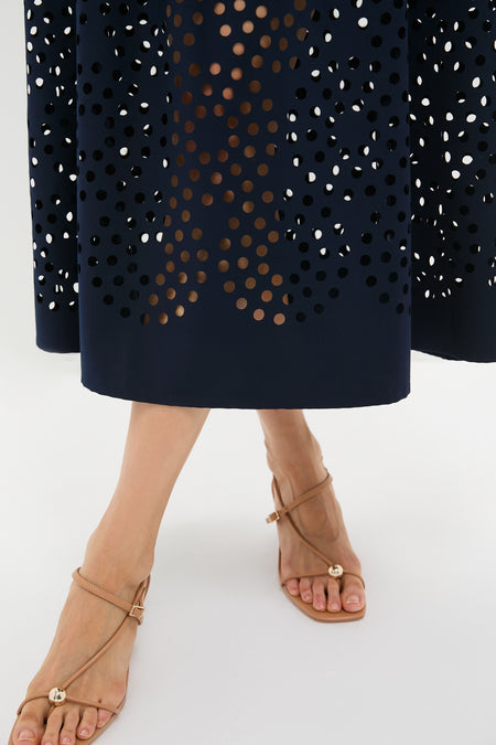 Classic Navy Astrid Midi Dress showcasing an effortless, high-end style with a laser-cut design, paired with fun, nude-tan strappy flat sandals featuring elegant gold details.