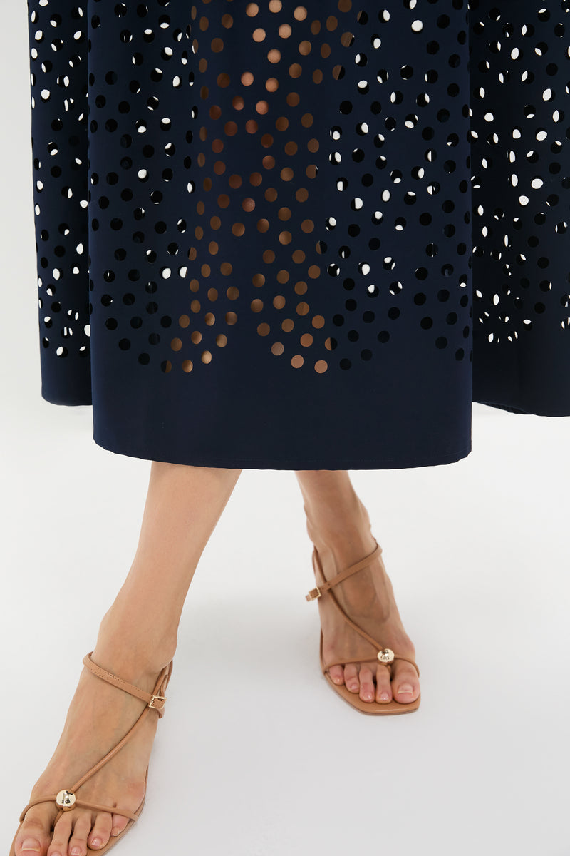 Classic Navy Astrid Midi Dress showcasing an effortless, high-end style with a laser-cut design, paired with fun, nude-tan strappy flat sandals featuring elegant gold details.