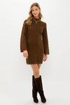 A woman in a Hyacinth House brown cable knit dress pairs it with dark brown knee-high boots for a timeless fall look.