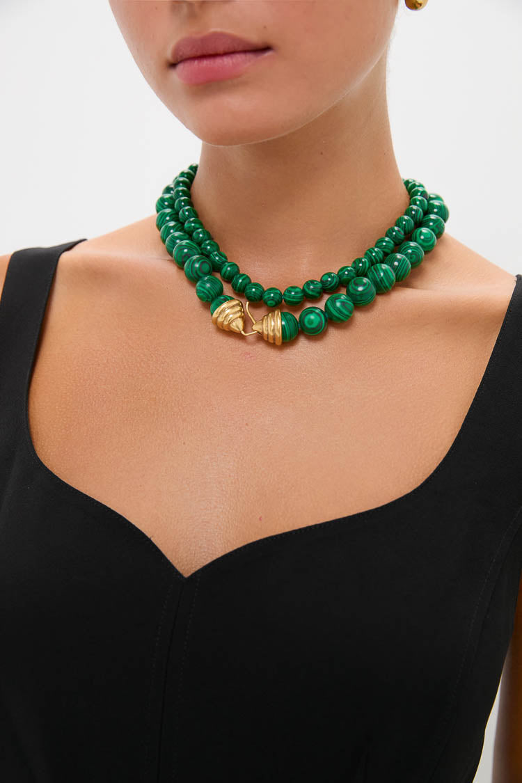 Woman wearing the classic Malachite Double Strand Celine Necklace with gold-tone clasp, paired with a black top. Effortless, fun, and high-end accessory for versatile styling.