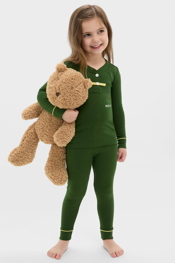 Young girl in classic Douglas Fir Pima Cotton Arien Kid's Pajama Set, hugging a teddy bear; effortless and fun design with high-end contrast trim details.