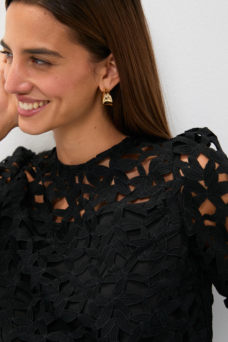 Smiling woman in the classic, high-end Black Lace Elodie Blouse with puff shoulders, showcasing an effortless and fun style for any occasion.