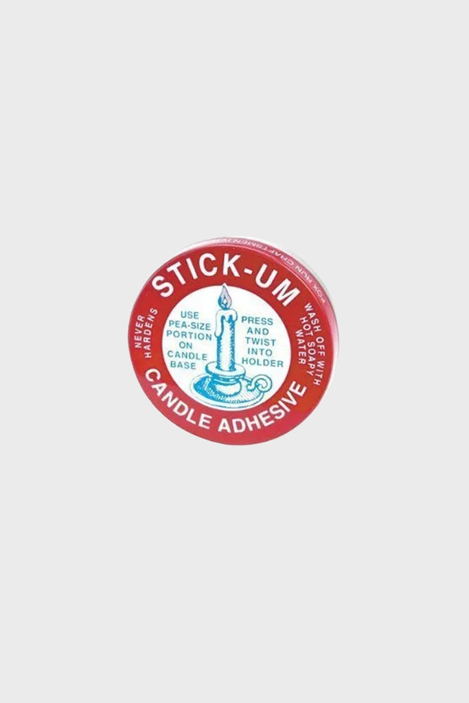 A round tin labeled Stick Ums Candle Adhesive features candle instructions and an illustration on the lid. Perfect for securing candles in any holder.
