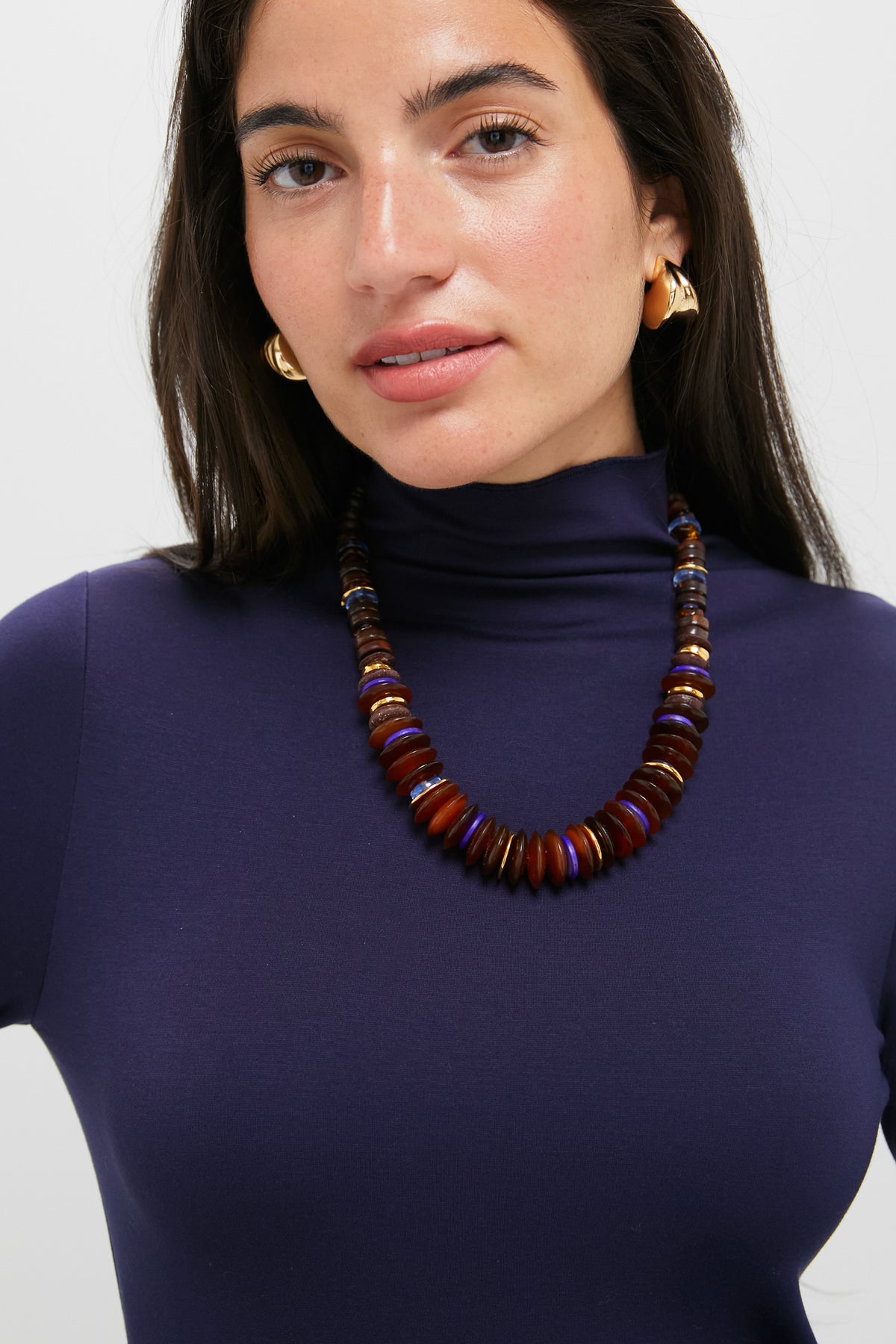Woman wearing the Multi Amaranth Necklace, a classic, high-end piece with warm-toned, disk-shaped beads. Effortlessly fun and perfect for any occasion.