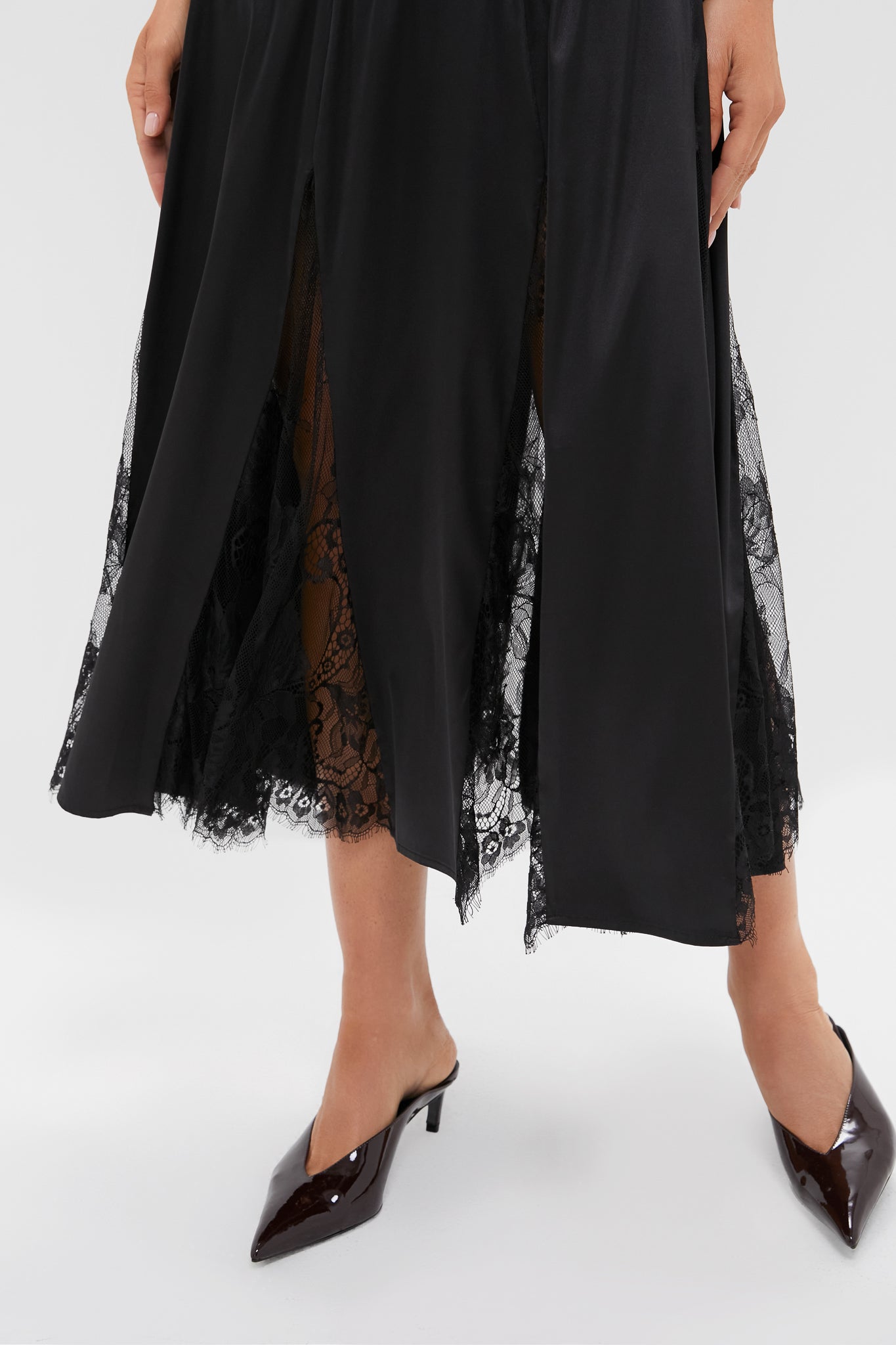 Black Mixed-Media Coco Maxi Dress with front slits and lace paneling, paired with patent-leather mules; a classic, effortless, and fun high-end look for evening occasions.