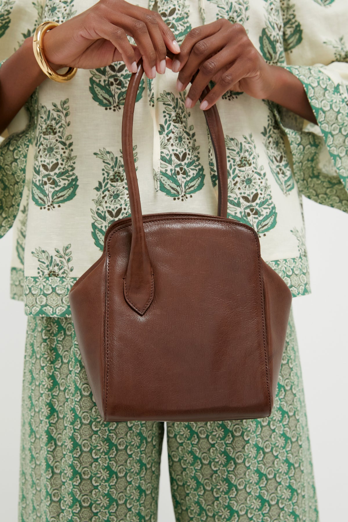Person holding the Dark Brown Leather Sporty Lady Bag with classic one-handle design, showcasing effortless elegance. The bag features silver-tone hardware and a playful charm.