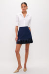 Model wearing the Navy Metallic Fringe Francie Mini Skirt, paired with a classic white shirt and gold strappy heels, exuding an effortless, high-end, and fun style.