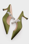 Fern Satin Mae Heels: classic olive-green satin pumps with jeweled Mary Jane strap, pointed toes, and mid-height stiletto heels, perfect for an effortlessly cool, high-end look.