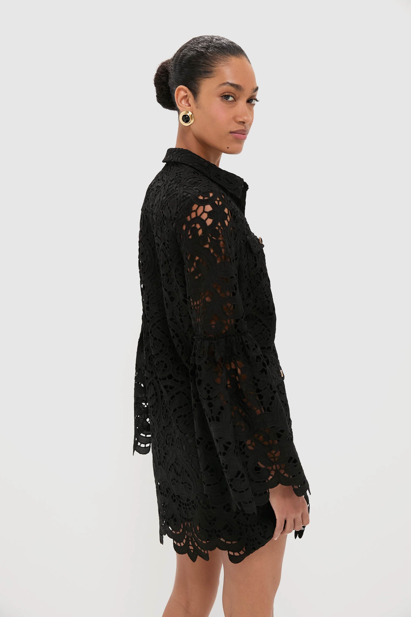 Woman in a Black Lace Long Sleeve Rachael Mini Dress with flared sleeves and scalloped hems, exuding classic, effortless style. Perfect for a chic, high-end look.