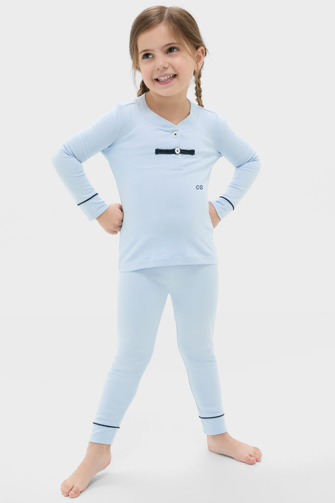 Young girl in classic, high-end Light Blue Pima Cotton Arien Kid's Pajama Set with decorative buttons and navy accents, embodying effortless fun and style.