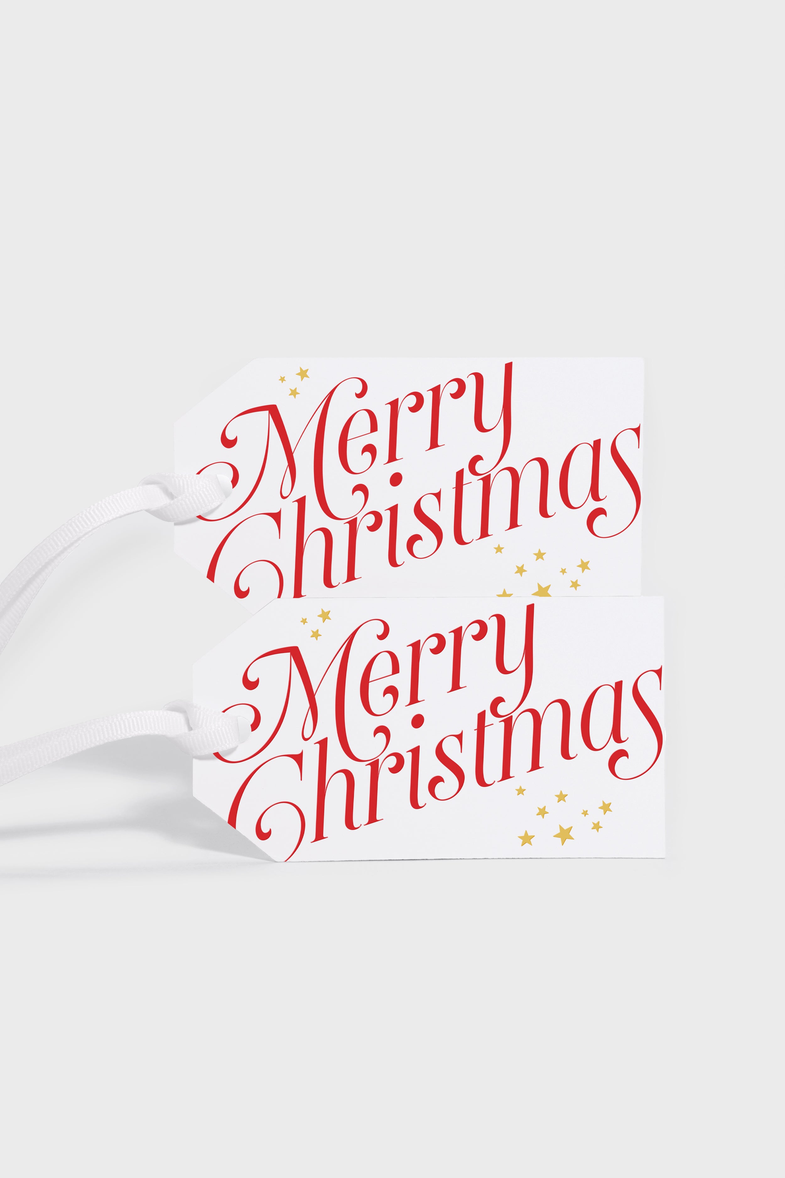 Two white Dear Annabelle Merry Gift Tags with “Merry Christmas” in red script and engraved stars, each attached to a white string—perfect for sharing Christmas spirit.