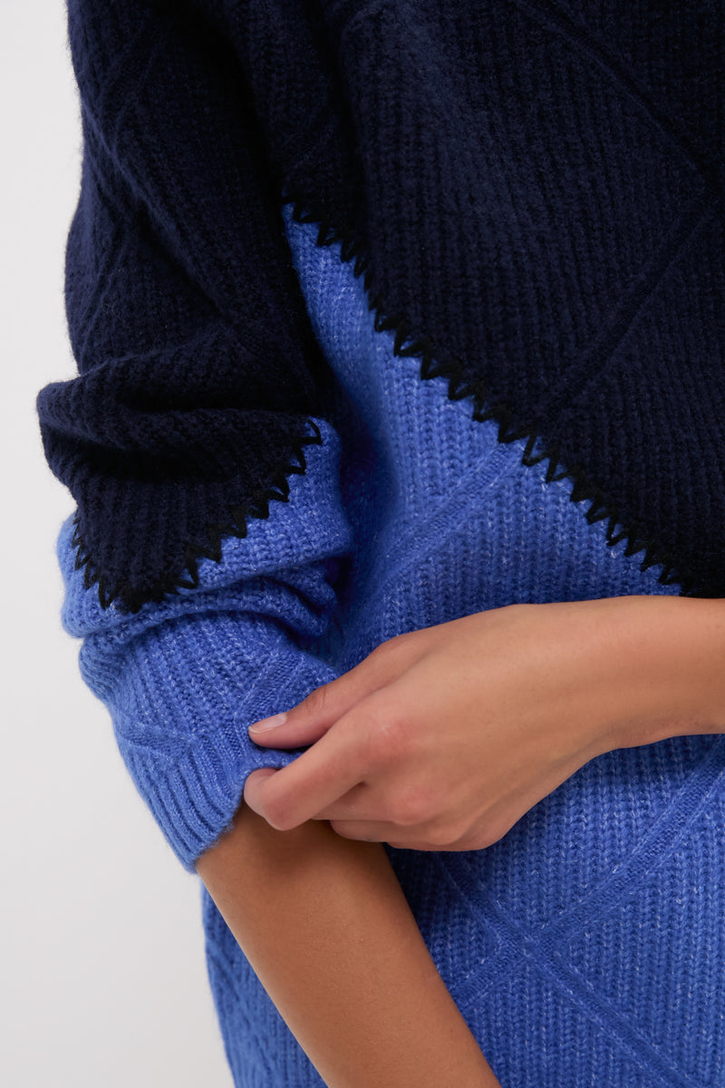 Adjusting the sleeve of a classic Navy & Cerulean Diamond Demi Turtleneck, paired with an effortless, high-end navy wrap, exuding a fun, confident Tuckernuck style.