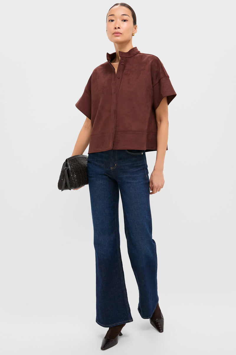 Model wears the Ganache Vegan Suede Trapunto Stitch Sofia Shirt, a classic, effortless top with trapunto stitched details, styled with flared jeans and a black clutch.