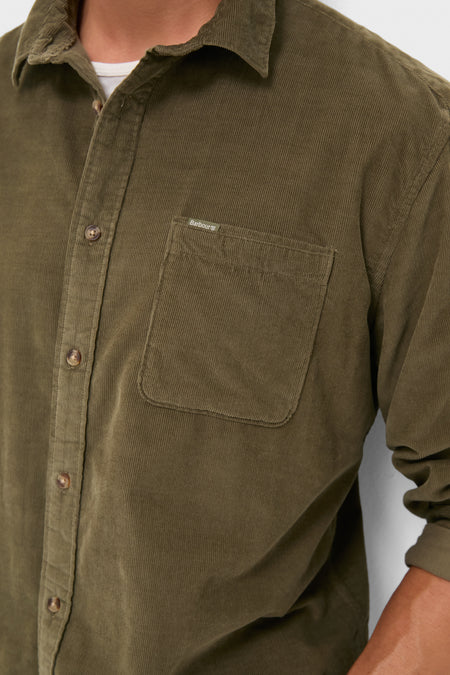Close-up of a classic, olive Bramside Relaxed Cord Shirt with a chest pocket, button placket, and rolled sleeve, embodying effortless, high-end style.