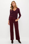 A woman stands against a white background wearing a burgundy V-neck sweater, Alex Mill burgundy corduroy pants, and dark brown boots—a classic fall look featuring Alex Mill.