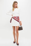 Woman styled in a classic, effortless look with the Scarlet Sakura Medium Silk Scarf tied sarong-style, elevating her outfit with fun, high-end flair.