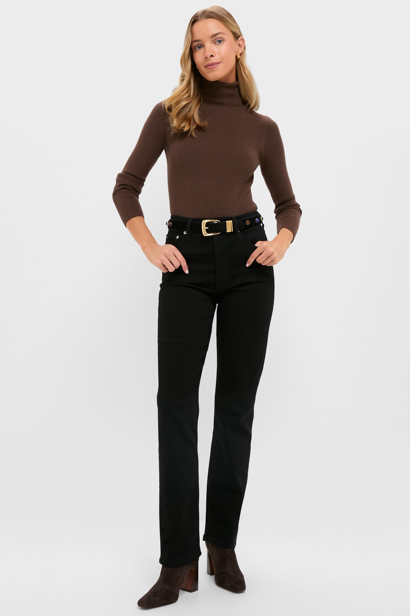 A woman faces forward in a brown turtleneck, AGOLDE high-rise straight-leg jeans with comfort stretch, a belt, and brown ankle boots, set against a plain white background.