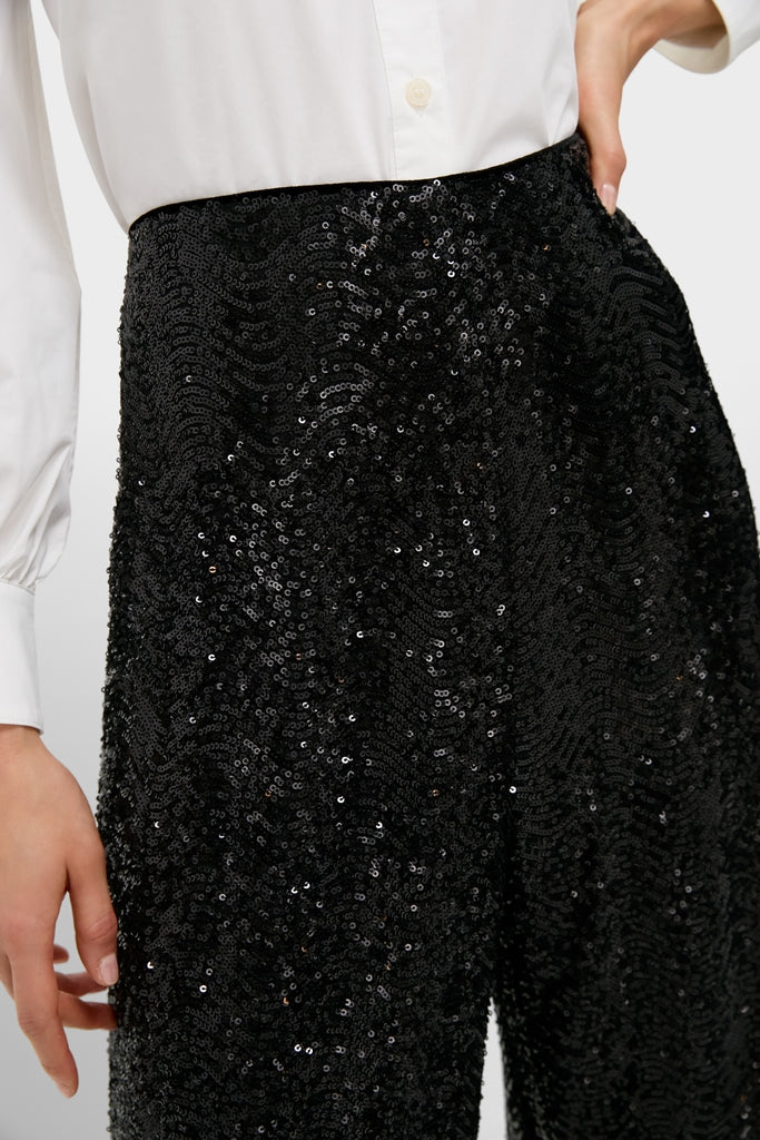 Black Sequin Tatum Pants, high-waisted and densely sequined, paired with a classic white shirt, exude effortless confidence and fun, embodying Tuckernuck's high-end style.