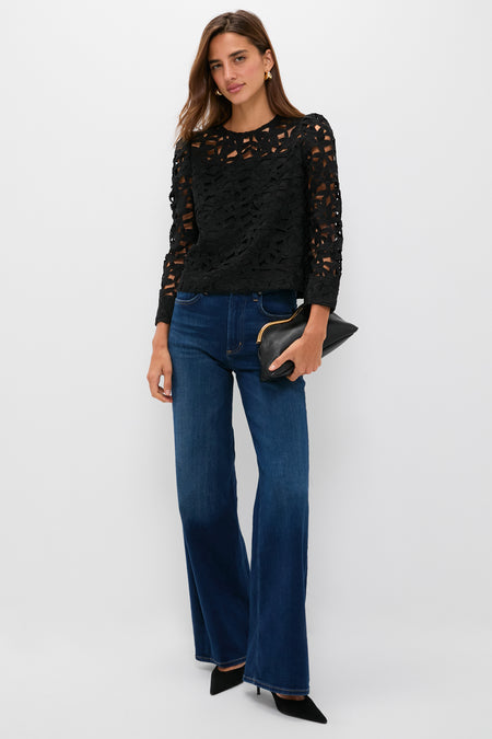 Model wearing the classic Black Lace Elodie Blouse with cut-out floral pattern, paired with high-waisted jeans and heels, embodying an effortless, high-end style.