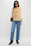 A person in sunglasses, blue jeans, brown boots, and a cream blouse layered with the Sea New York beige wool reversible vest with ribbon ties, carrying a brown shoulder bag, stands against a white background.