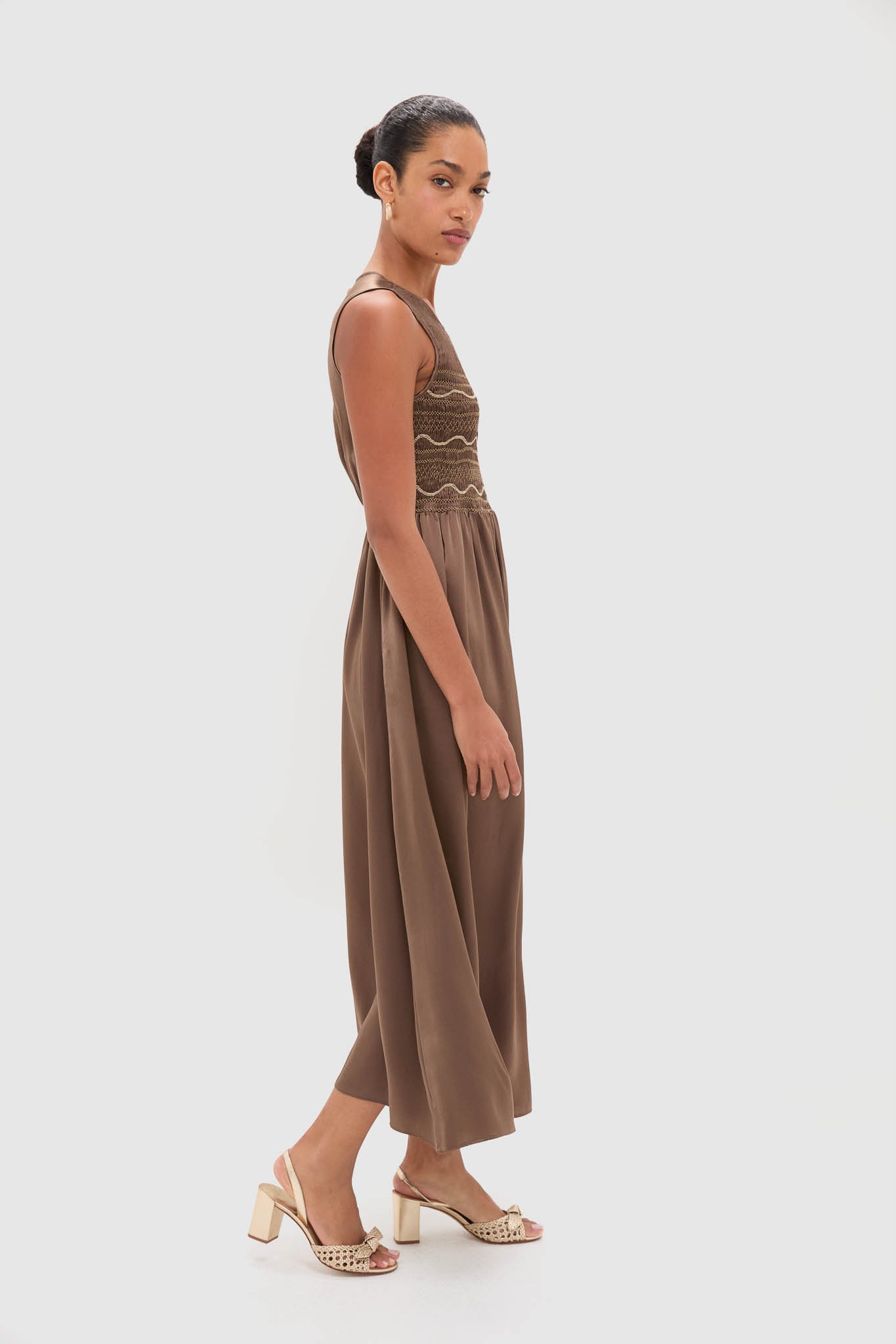 Regio Brown Silk Gioia Midi Dress features a classic, effortless silhouette with a smocked bodice and flowing skirt, paired with fun, high-end block-heel sandals.