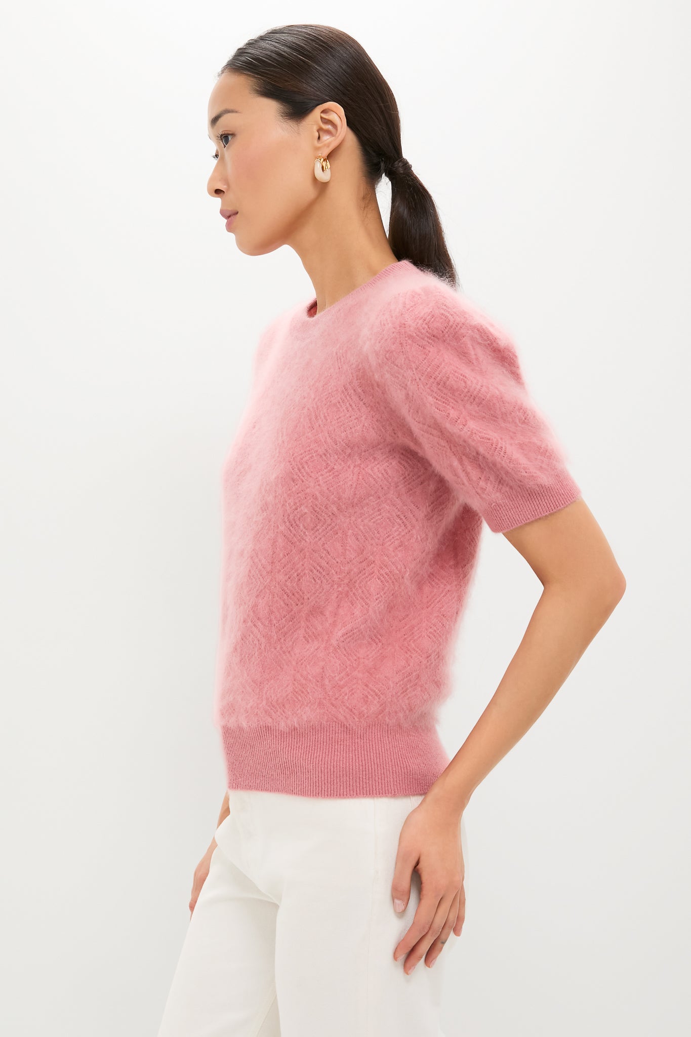 Woman in a classic, high-end Dusty Rose Brushed Merino Wool Puff Sleeve Lexie Sweater, paired with white trousers, exuding an effortless and fun style.