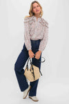 Woman wearing Reissue Mid Rise Relaxed Straight Harper Jean, styled effortlessly with a floral blouse, casual loafers, and a chic straw handbag, showcasing classic, high-end fashion.