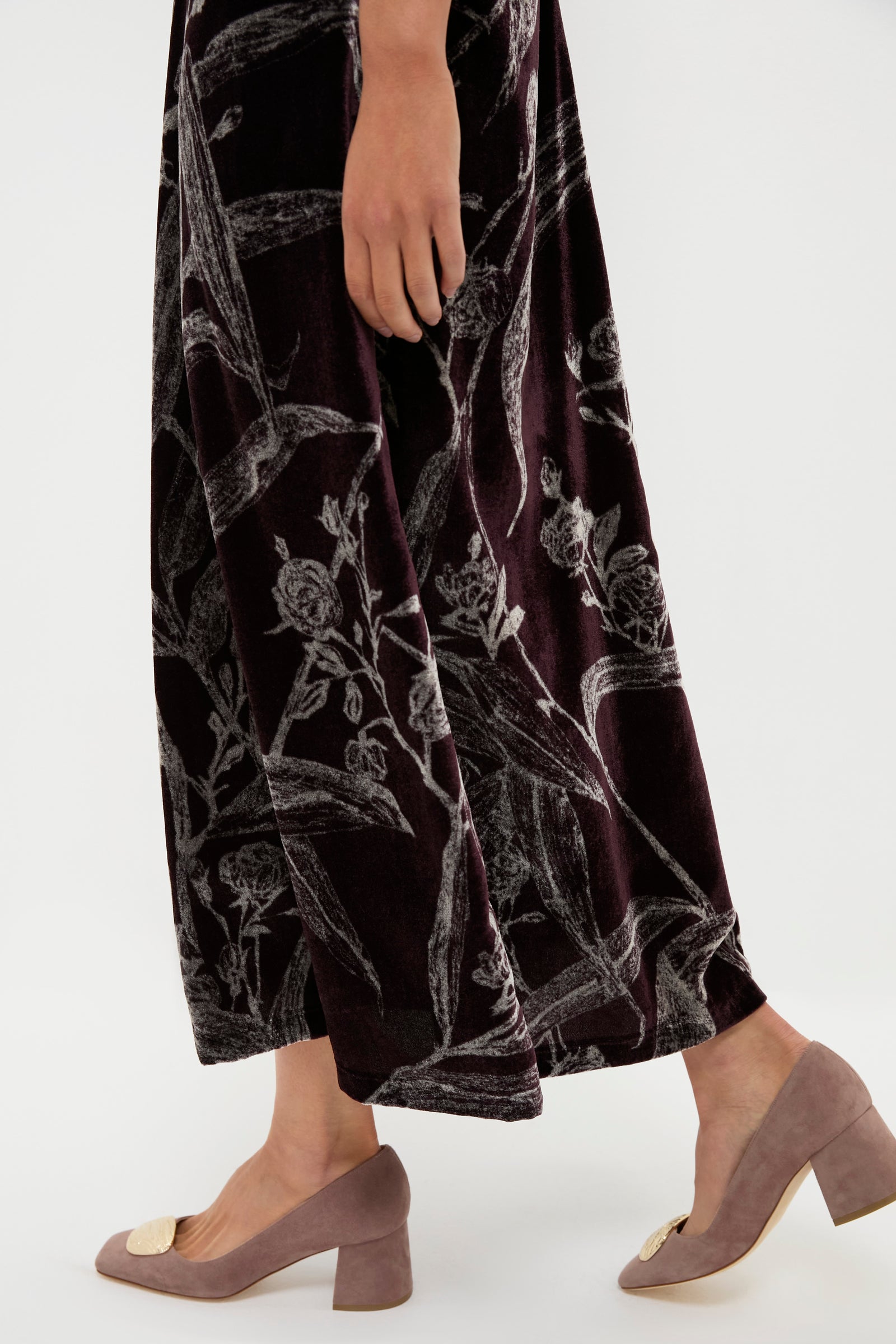 A person in a dark, patterned La DoubleJ skirt and mauve low-heeled shoes walks on a light background, capturing the brand's signature chic flair.