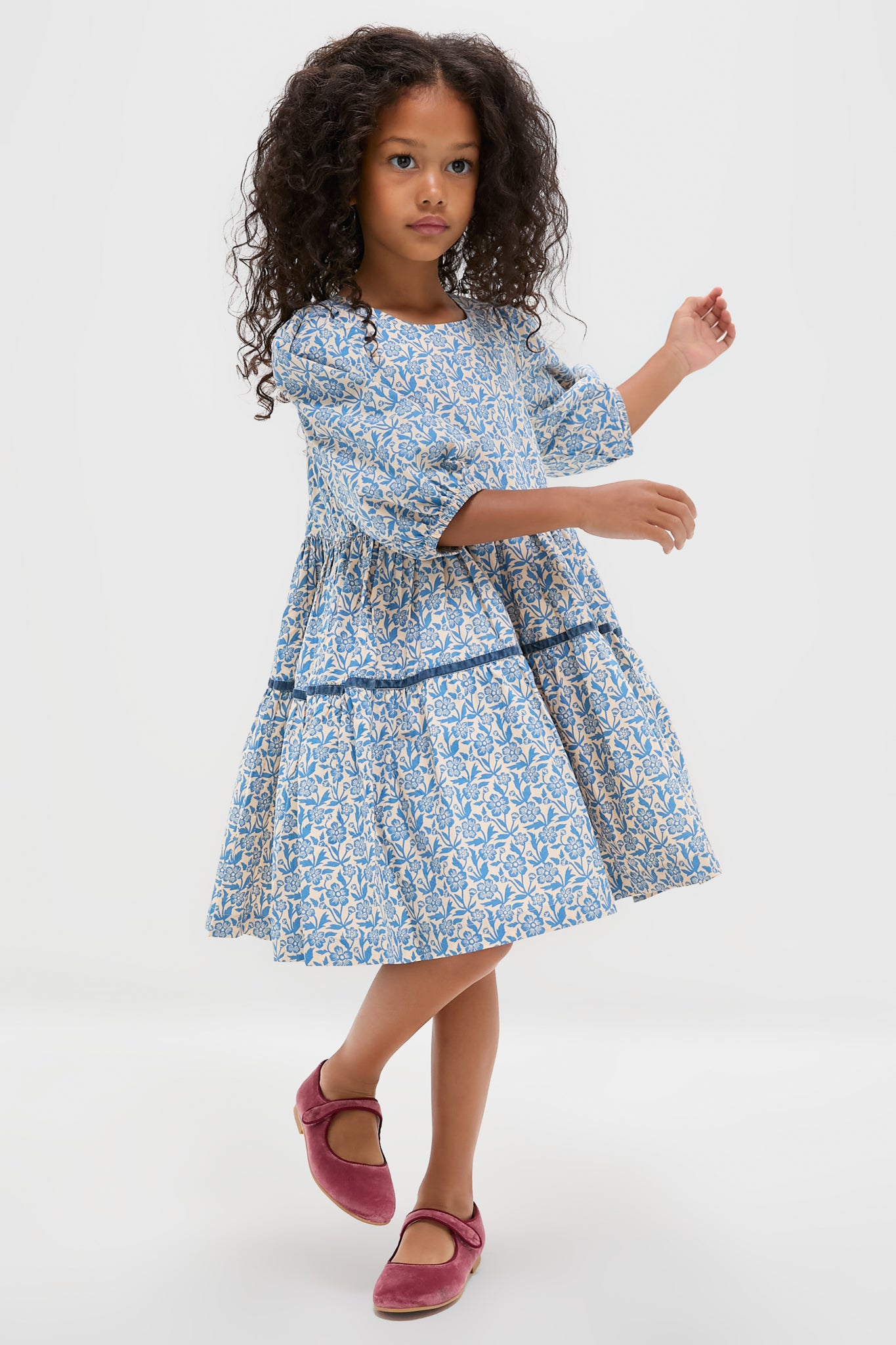Young girl in a blue floral dress, wearing classic, effortlessly stylish Dusty Pink Girl Velvet Mary Janes with a fun, high-end velvet finish and velcro strap.