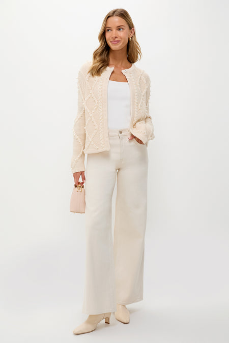Young woman models the Cream Cable Knit Pearl Collins Cardigan, featuring a classic diamond cable pattern and pearl details, styled effortlessly with high-end, fun, winter whites.