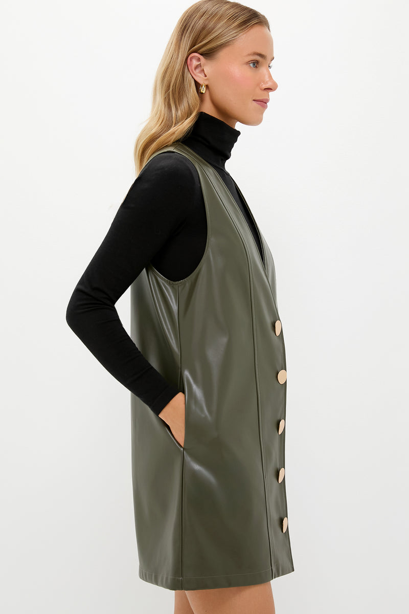Woman models Olive Faux Leather Pinafore Dress with gold-tone buttons, layered over black turtleneck. Classic, effortless, high-end style for fun, versatile occasions. Perfect for cooler weather.
