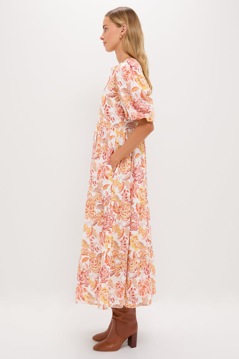 Saffron Floral Cisco Maxi Dress: A classic, effortless tiered dress with puff sleeves and floral print, styled with brown boots for a fun, high-end look.
