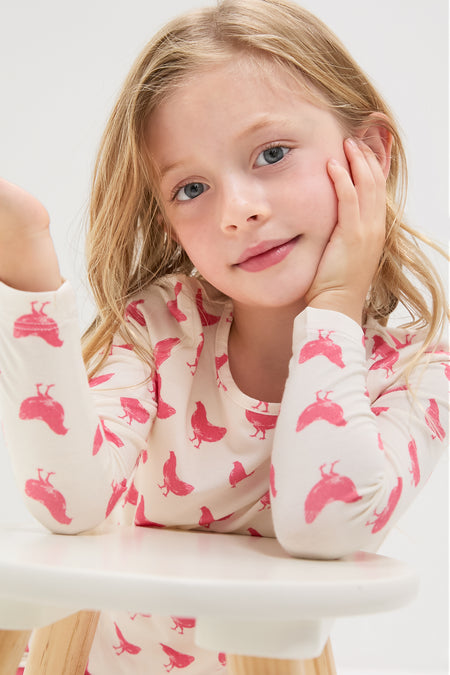 Young child in Pink Chickens Kids Bamboo Pj Set, featuring a classic, effortless design with a pink bird pattern, embodies fun and high-end comfort.