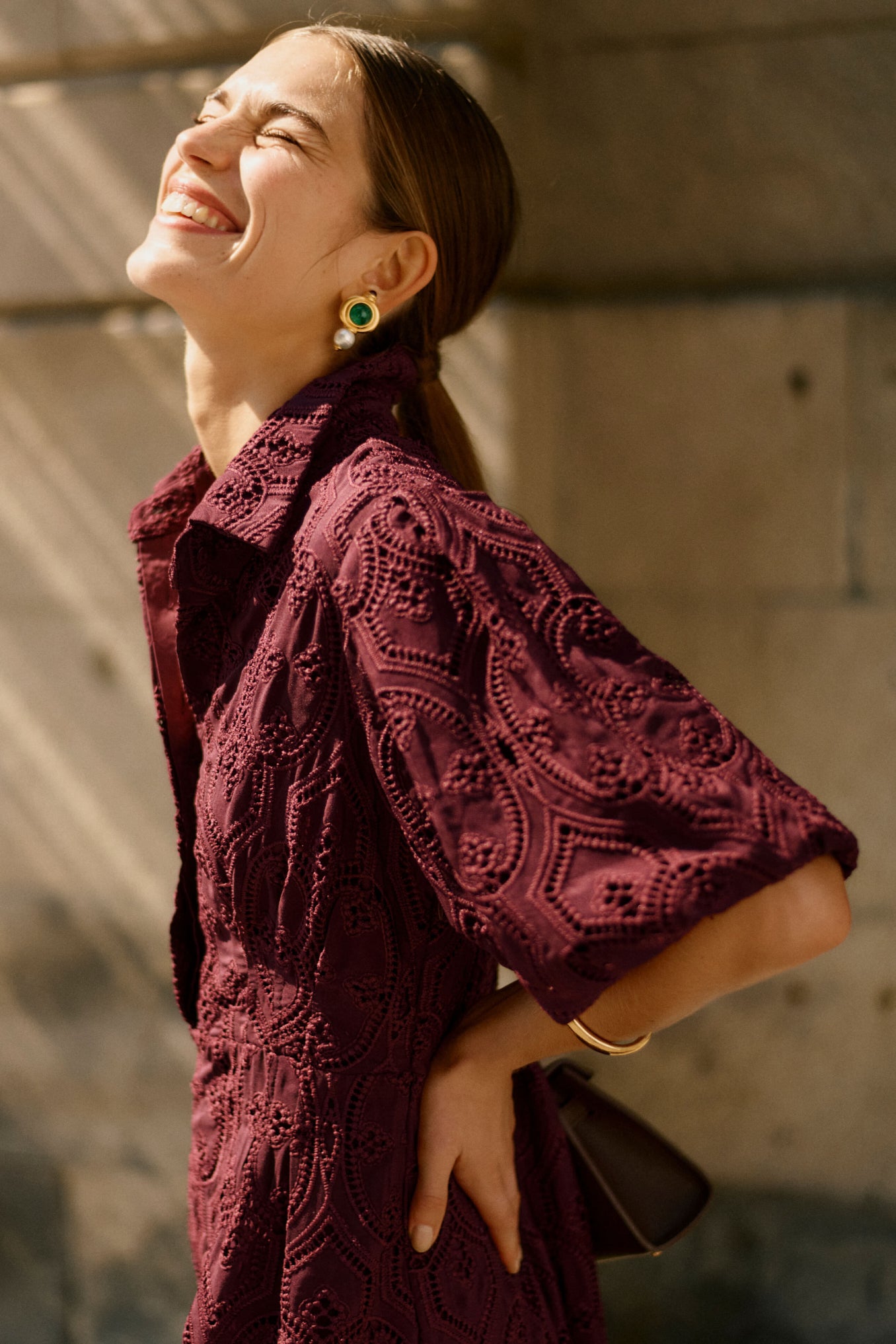Woman in a burgundy dress laughing towards the sun 