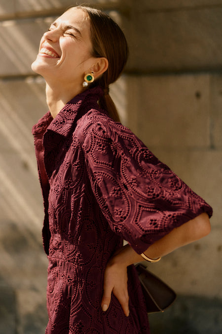 Woman in a burgundy dress laughing towards the sun 