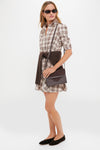 Woman in a plaid shirtdress, effortlessly styled with a classic, high-end brown Leather Stevie Crossbody, featuring a woven suede flap and practical crossbody strap.