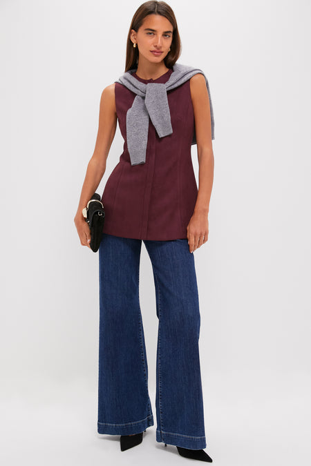 Woman models Winetasting Vegan Suede Rhoda Tunic Top, styled with a gray sweater, wide-leg jeans, black heels, and gold hoop earrings, exuding effortless, high-end, classic style.