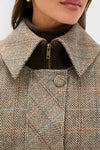 Close-up of a woman's upper torso wearing a classic Herringbone Stewart Poncho with subtle checks and a rib-knit sweater, capturing an effortless, high-end fall layering style.