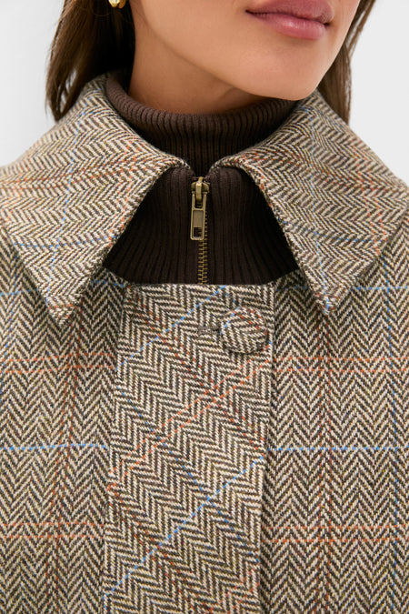 Close-up of a woman's upper torso wearing a classic Herringbone Stewart Poncho with subtle checks and a rib-knit sweater, capturing an effortless, high-end fall layering style.