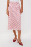 A person wears a Hyacinth House light pink shimmer stripe skirt with matching pink heeled mules, creating a festive look perfect for a holiday party.
