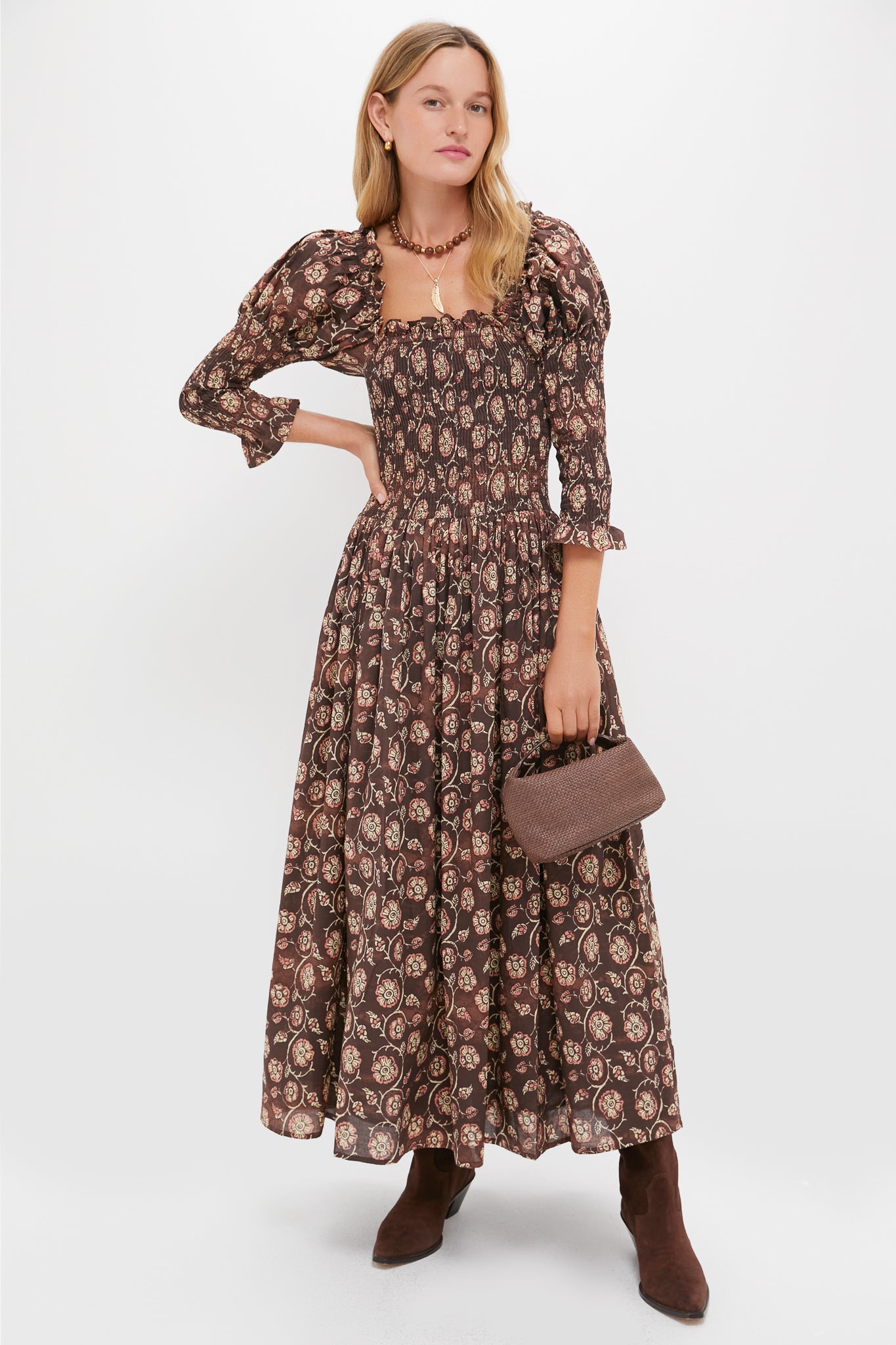Model in a classic, floral-print dress and boots, holding a woven handbag, showcasing the effortless, fun style of Tuckernuck's Wood and Gold Beaded Necklace.