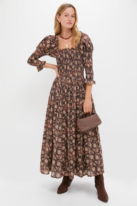 Model in a classic, floral-print dress and boots, holding a woven handbag, showcasing the effortless, fun style of Tuckernuck's Wood and Gold Beaded Necklace.